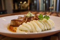Pork Chop Steak Vepřová Kotleta Sliced Pork Chop Steak Vepřová Kotleta topped with herb butter, served with piped mashed potato and parsley.