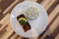 Blackened Salmon Blackened Salmon fillet with lemon wedge and herb garnish beside a mound of rice on a white plate