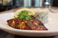Blackened Salmon Blackened Salmon fillet on a plate with herbed rice, lemon wedge, and parsley garnish