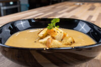 Cauliflower Soup Bowl of Cauliflower Soup topped with golden croutons and a parsley sprig, on a wooden table