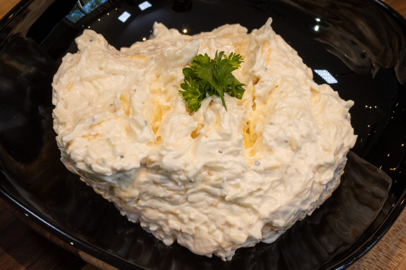 Mound of Cheese – Garlic Dip and Spread with parsley garnish on a black plate.