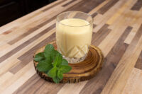 Glass of Czech Egg Liqueur – Czech Eggnog with ice, on a wood slice with fresh mint.