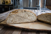 Sliced Czech Rye Bread loaf with dark crust and airy crumb on a wooden board.
