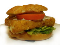 Fried Cheese in a kaiser roll, melted cheese running from the breading, with tomato and lettuce.