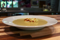 Bowl of creamy Broccoli Soup topped with crunchy croutons on a wooden table.