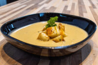 Cauliflower Soup Bowl of Cauliflower Soup topped with golden croutons and a parsley sprig on a wooden table
