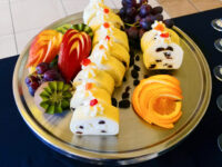 Sliced Cheese Roulade with Goat Cheese & Raisins on a platter with fresh fruit garnish.