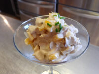 Chicken Salad Chicken Salad with creamy dressing and chopped chives, served in a stemmed glass on a steel counter.