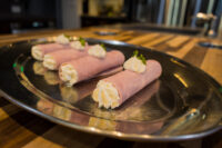 Six Creamy Horseradish Ham Rolls piped with cream filling and herb garnish on a metal platter