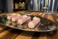 Four Creamy Horseradish Ham Rolls piped with cream filling and herb garnish on a metal platter.