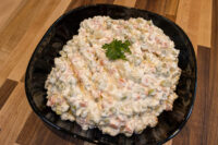 Bowl of Vlašský Salát Vlašák Czech deli salad with peas, diced carrot, and parsley garnish