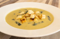 Leek Soup White bowl of creamy Leek Soup topped with golden croutons and thin strips of dark greens.