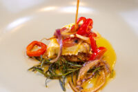 Skewered Nakládaný Hermelín cheese with red pepper, onion and rosemary in oil on a plate.
