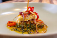 Seared block of Pickled Brie Cheese Nakladany Hermelin with pickled onion, chili, and rosemary in oil.