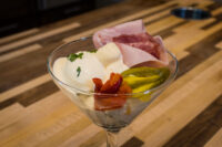 Russian Eggs (Ruské Vejce) layered in a martini glass with ham, pickle, roasted pepper, and creamy sauce
