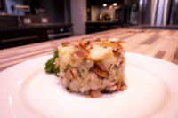 Rustic Crushed Potatoes with Bacon and Onion Molded Rustic Crushed Potatoes with Bacon and Onion, garnished with parsley on a white plate