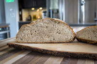 Sliced Czech Rye Bread showing its dense crumb, on a bark-edged wooden board.
