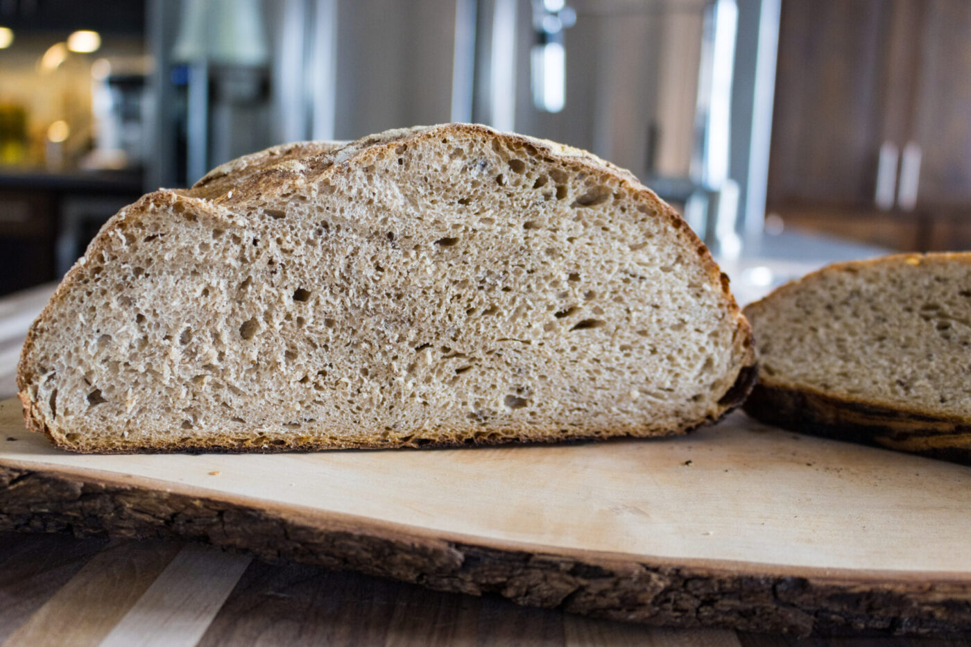 Cross-section of Czech Rye Bread showing a speckled crumb and seeded crust on a wood board.
