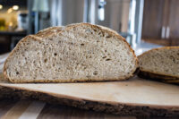 Cross-section of Czech Rye Bread showing a speckled crumb and seeded crust on a wood board.
