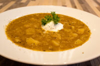 Bowl of Czech Sauerkraut Soup Zelňačka with potato chunks, a sour cream dollop, and a parsley sprig on top
