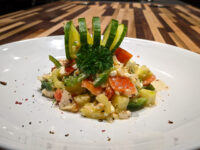 Shopska Salad Shopska Salad with diced tomato, feta cubes, and green pepper, topped with a cucumber ribbon curl and parsley.