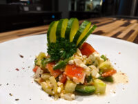 Shopska Salad Shopska Salad on a white plate with diced tomato, cucumber, feta, and a fanned cucumber garnish.