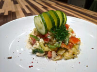 Shopska Salad Shopska Salad with diced red and green peppers and creamy feta, topped with a cucumber fan and parsley.