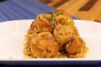 White plate stacked with golden bobalky buns topped with pale sauerkraut strands and a herb sprig.
