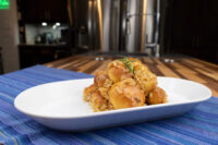 Golden bobalky with sauerkraut piled on a white plate, garnished with a herb sprig, on a blue mat.