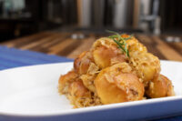 Bobalky with Sauerkraut piled on a white plate, garnished with a small herb sprig, set on a blue placemat.