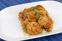 Golden Bobalky with Sauerkraut piled on a white plate, glazed in butter and garnished with a rosemary sprig.