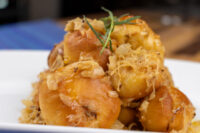 Golden bobalky with sauerkraut piled on a white plate, garnished with a rosemary sprig.