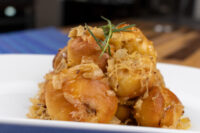 Stacked golden Bobalky with Sauerkraut topped with browned shredded sauerkraut and a rosemary sprig on a white plate
