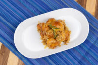 Bobalky with Sauerkraut: glazed dough pieces over sauerkraut strands, garnished with rosemary, on a white oval plate.