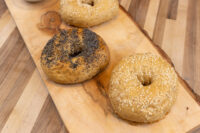 Three seeded bagels topped with poppy, sesame, and mixed seeds on a wooden board