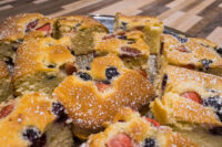 Cut squares of Bublanina (Czech Bubble Cake) with strawberries and blueberries, dusted with powdered sugar.
