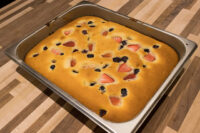 Baked Bublanina (Czech Bubble Cake) with strawberries and blueberries in a metal pan.