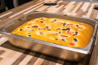 Golden Bublanina (Czech Bubble Cake) with strawberries and blueberries baked in a metal pan on a wood table