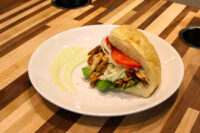Chicken Gyros sandwich with grilled chicken strips, lettuce, tomato and onion in a crusty roll.