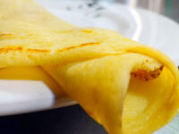 Folded Crepes with a browned filling visible inside, resting on a white plate.