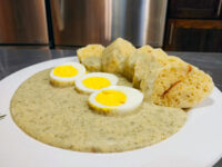 Bowl of Czech Dill Sauce Koprová Omáčka with sliced boiled egg and bread on a white plate.