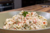 Bowl of Czech Potato Salad with diced potatoes, carrots, peas, and creamy dressing, topped with parsley