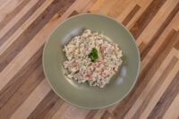 Bowl of Czech Potato Salad with diced vegetables and parsley on a wood table.