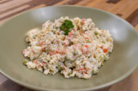 Bowl of Czech Potato Salad with diced potatoes, peas, and carrots in creamy dressing, topped with parsley.