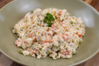 Bowl of Czech Potato Salad with diced potatoes, carrots, peas, and a parsley garnish.