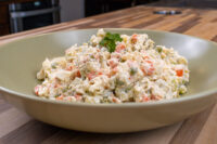 Bowl of Czech Potato Salad with diced vegetables and creamy dressing, garnished with parsley.