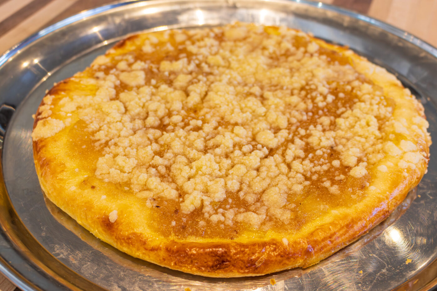 Whole frgal kolach with golden crust and crumbly streusel topping on a metal tray