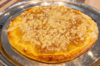 Whole frgal kolach with golden crust and crumbly streusel topping on a metal tray