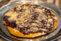 Baked Frgal Kolach with Plum Filling, dark filling and streusel crumbles in a glass pie dish