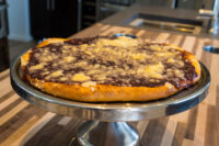Round Frgal Kolach with Plum Filling topped with streusel, displayed on a metal cake stand.